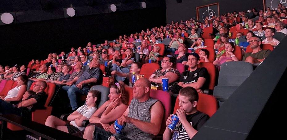 Kinderen en ouders die in een volle bioscoopzaal kijken naar hun eindfilm van groep 8